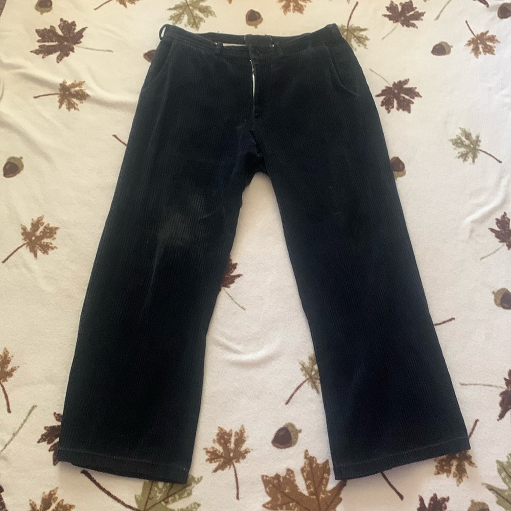 Men’s corduroy black pants with button, zipper, and pockets.